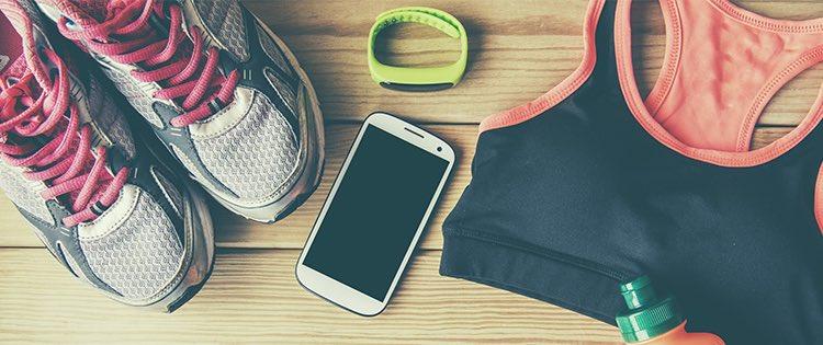 Photo of sneakers, a smartphone, a sports bra, and other workout gear laid out on a table