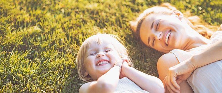 Photo a mother and her toddler smiling and laying on the grass outside
