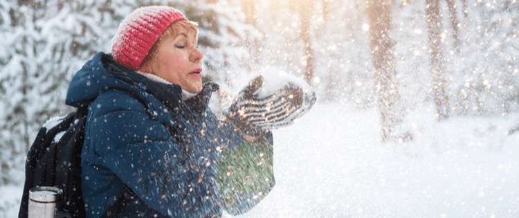 Photo of a middle aged woman blowing snow out of her hands