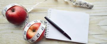 Photo of two apples, a notepad, and a tape measure