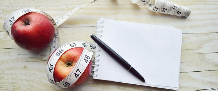 Photo of two apples, a notepad, and a tape measure