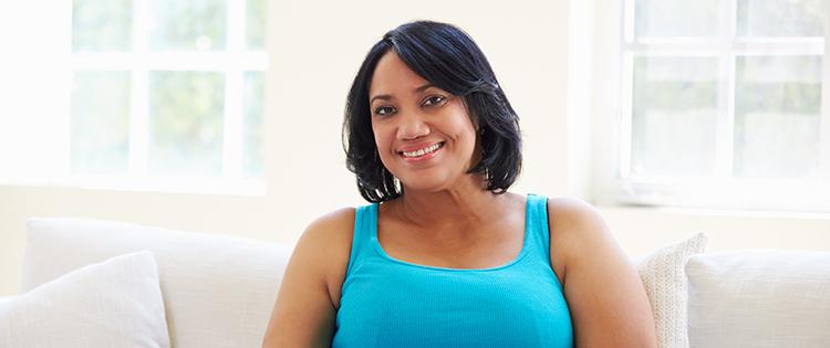 Photo of an African American woman smiling while sitting on a couch