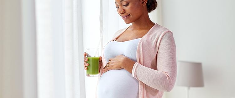 Photo of a pregnant black woman with a smoothie
