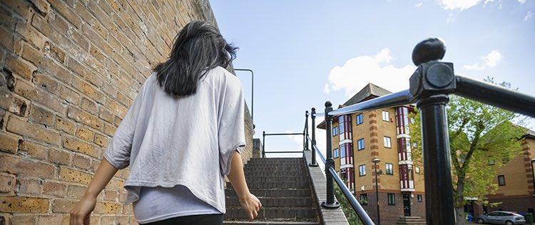 Photo of a woman with dark hair walking up outdoor stairs in a city