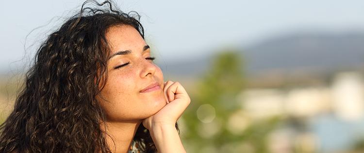 Woman of a young Hispanic woman sitting outside with her eyes closed