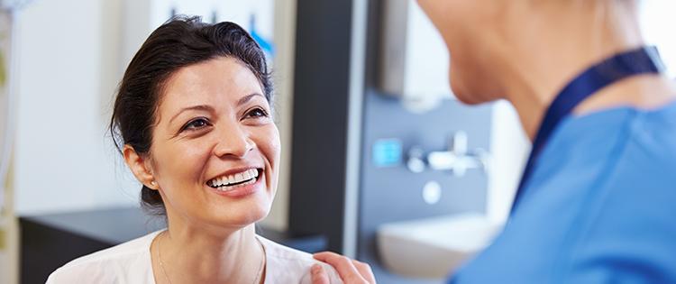 Photo of a dark haired middle aged woman talking to a healthcare provider