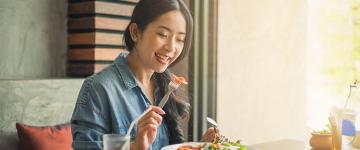 Photo of an Asian woman eating a salad at a restaurant