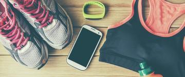 Photo of sneakers, a smartphone, a sports bra, and other workout gear laid out on a table