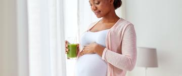 Photo of a pregnant black woman with a smoothie