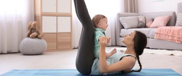 Photo of a woman on a yoga mat with her baby at home