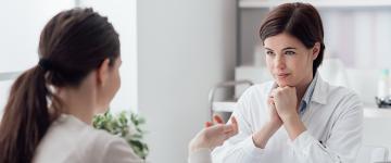 Photo of a woman speaking to a listening doctor