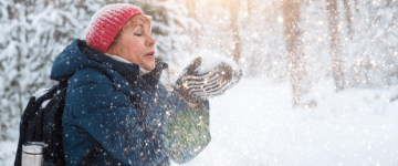 Photo of a middle aged woman blowing snow out of her hands